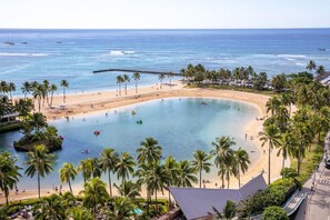 A beach resort with a large pool, palm trees, and a view of the ocean.