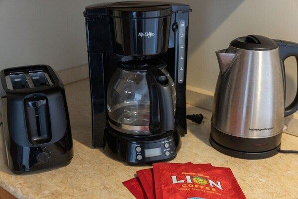 A kitchen with a coffee maker, toaster, and kettle.