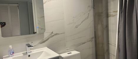 A bathroom with a white sink, mirror, and shower area.