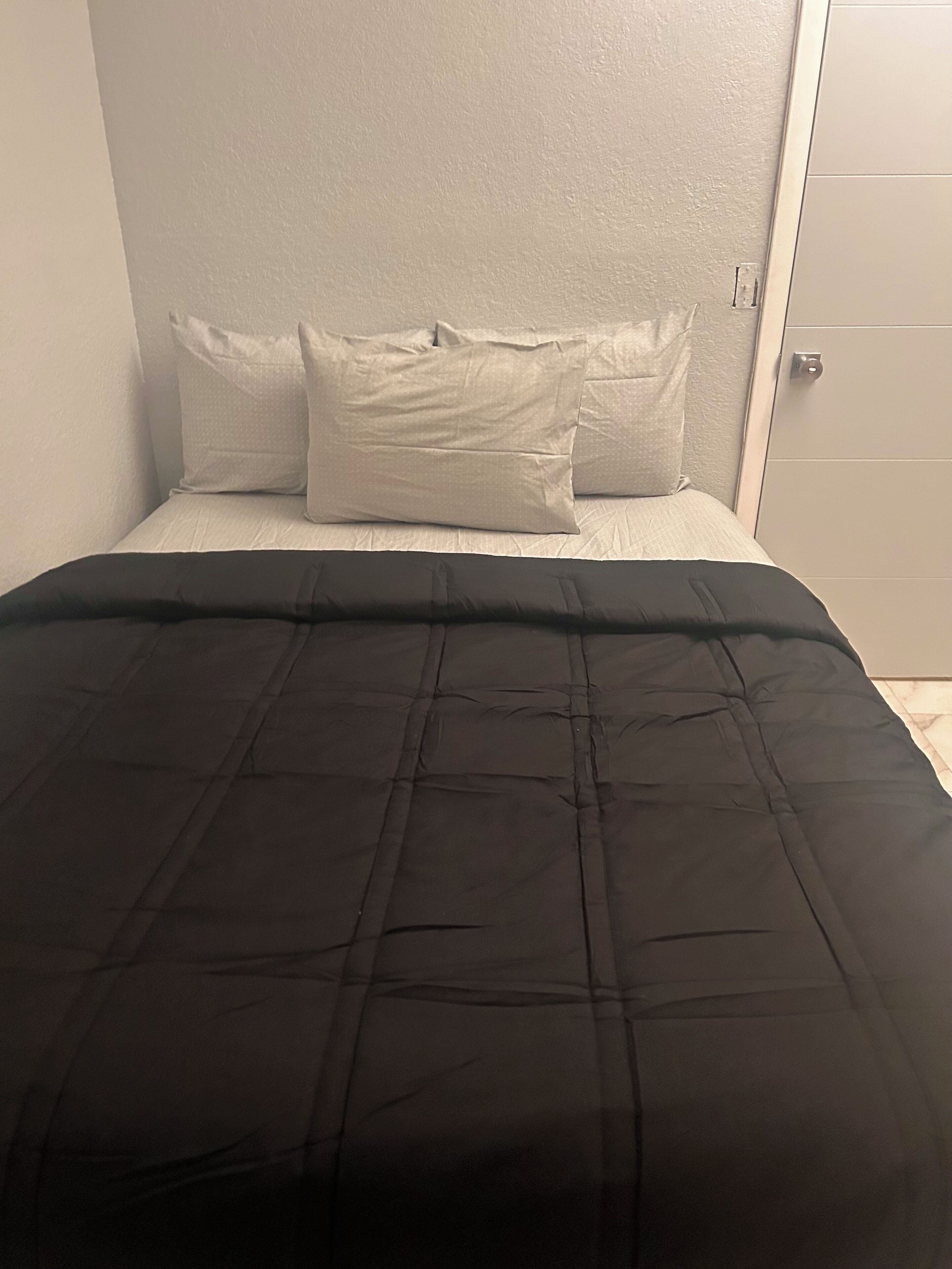 A bed with a black bedspread and two white pillows.