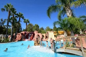 A swimming pool with palm trees and a water slide.