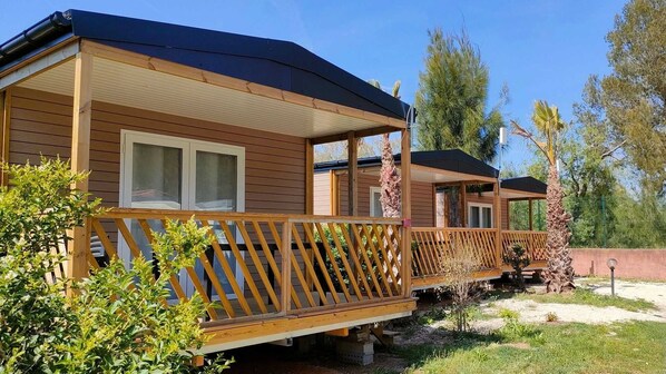 A row of wooden cabins with balconies, each featuring a window and a covered porch area.