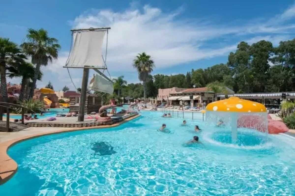A swimming pool with water slides and palm trees in the background.