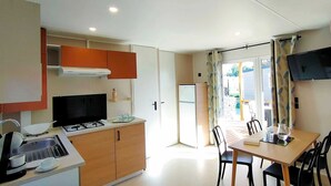 A compact kitchen with a gas stove, sink, and cabinets, leading to a dining area with a table and chairs.