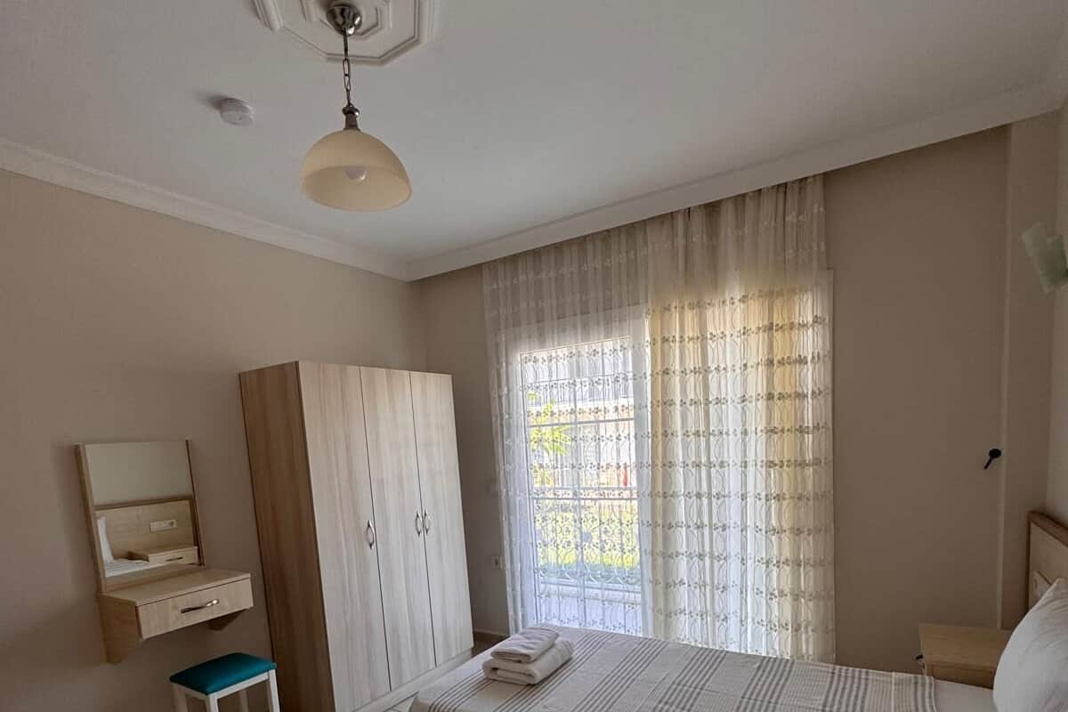 Un dormitorio con dos camas, un armario, un espejo y una ventana con cortinas.