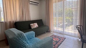 A living room with a sofa, a chair, a patterned rug, and a ceiling light fixture. - MERMAID PANSIYON (Marmaris)