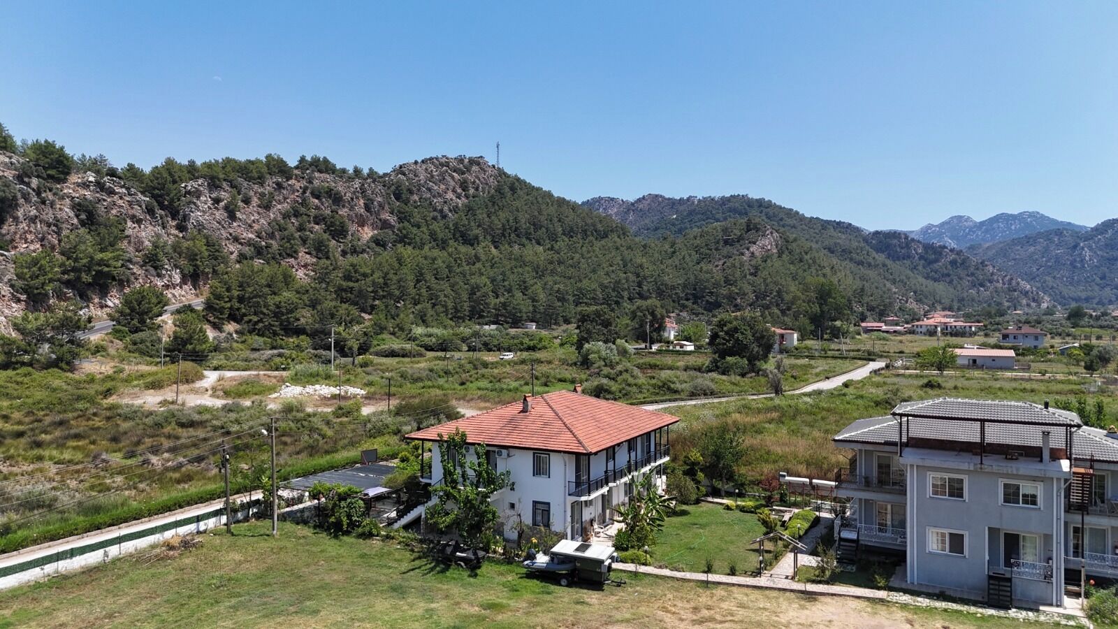 A residential area with houses, a road, and a mountainous backdrop.
