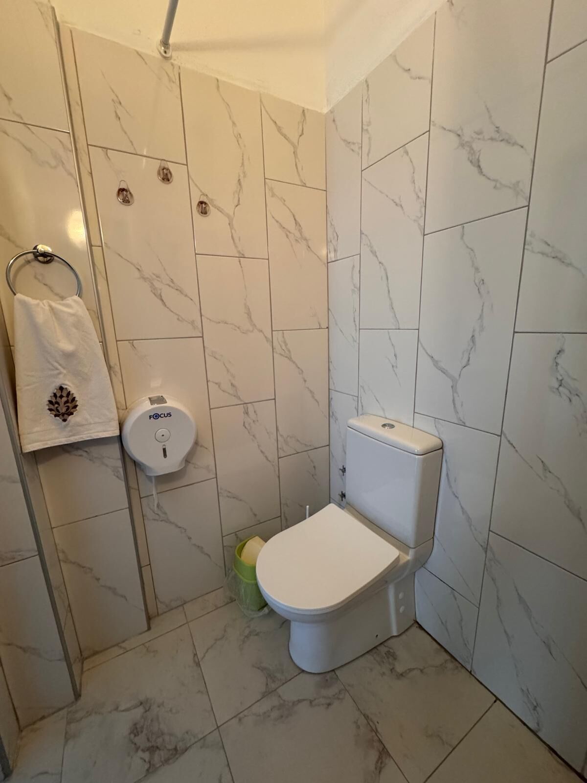 A bathroom with a toilet, a hand dryer, and a towel rack.