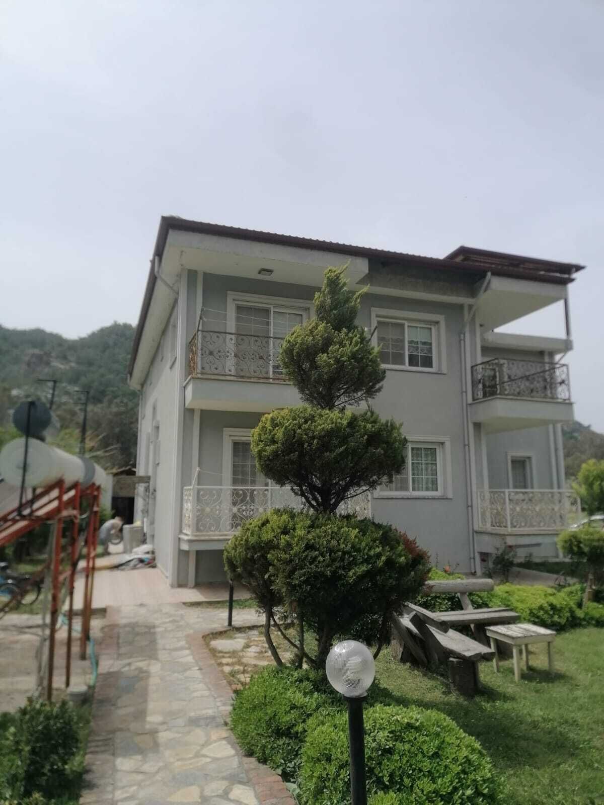 Un edificio de varios pisos con balcones, un jardín cuidado y un camino de piedra.