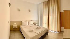 A hotel room with a bed, bedside tables, a wardrobe, and a window with curtains. - MERMAID PANSIYON (Marmaris)