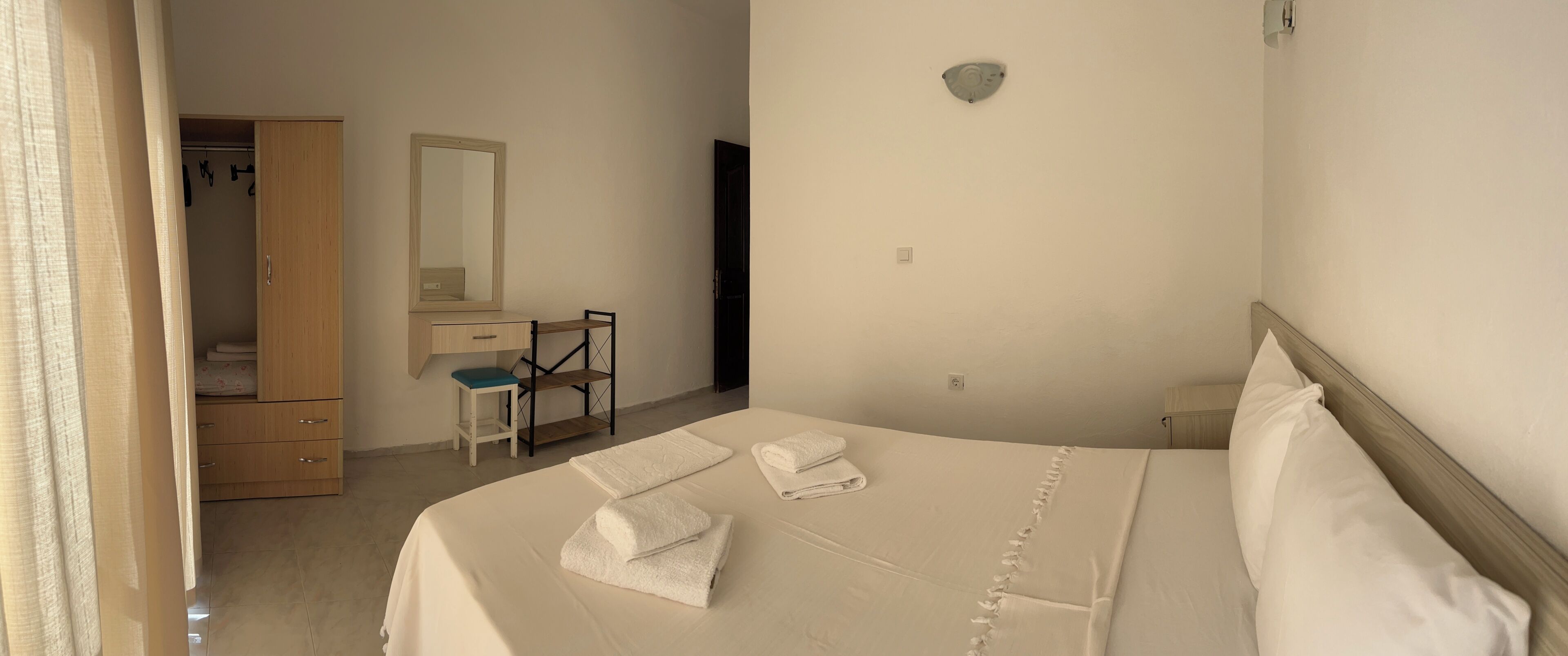 Un dormitorio con cama, escritorio, silla, armario y espejo.