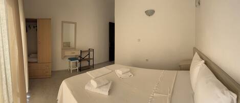 Un dormitorio con cama, escritorio, silla, armario y espejo.