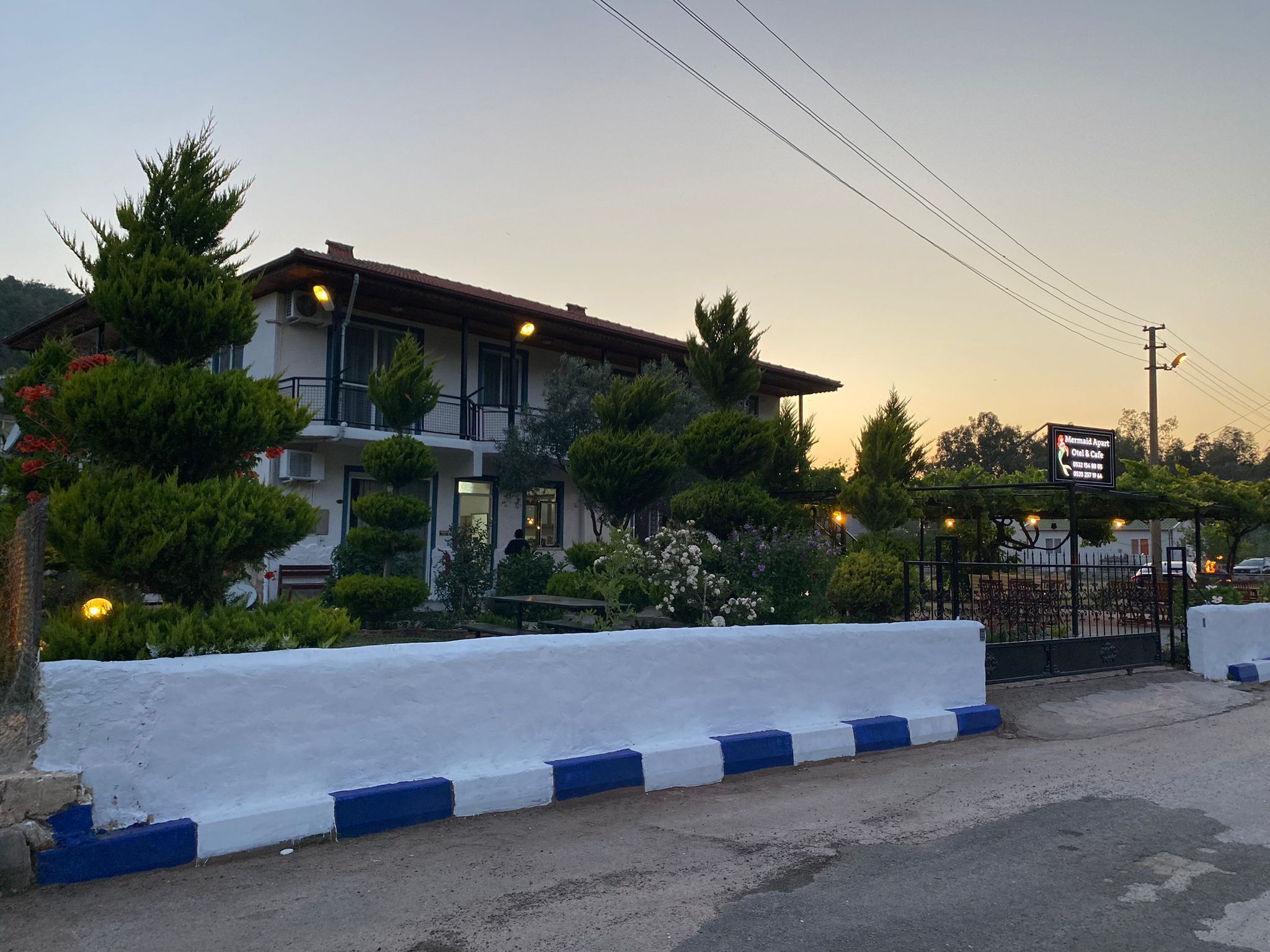 A hotel with a white facade, multiple windows, and a balcony.