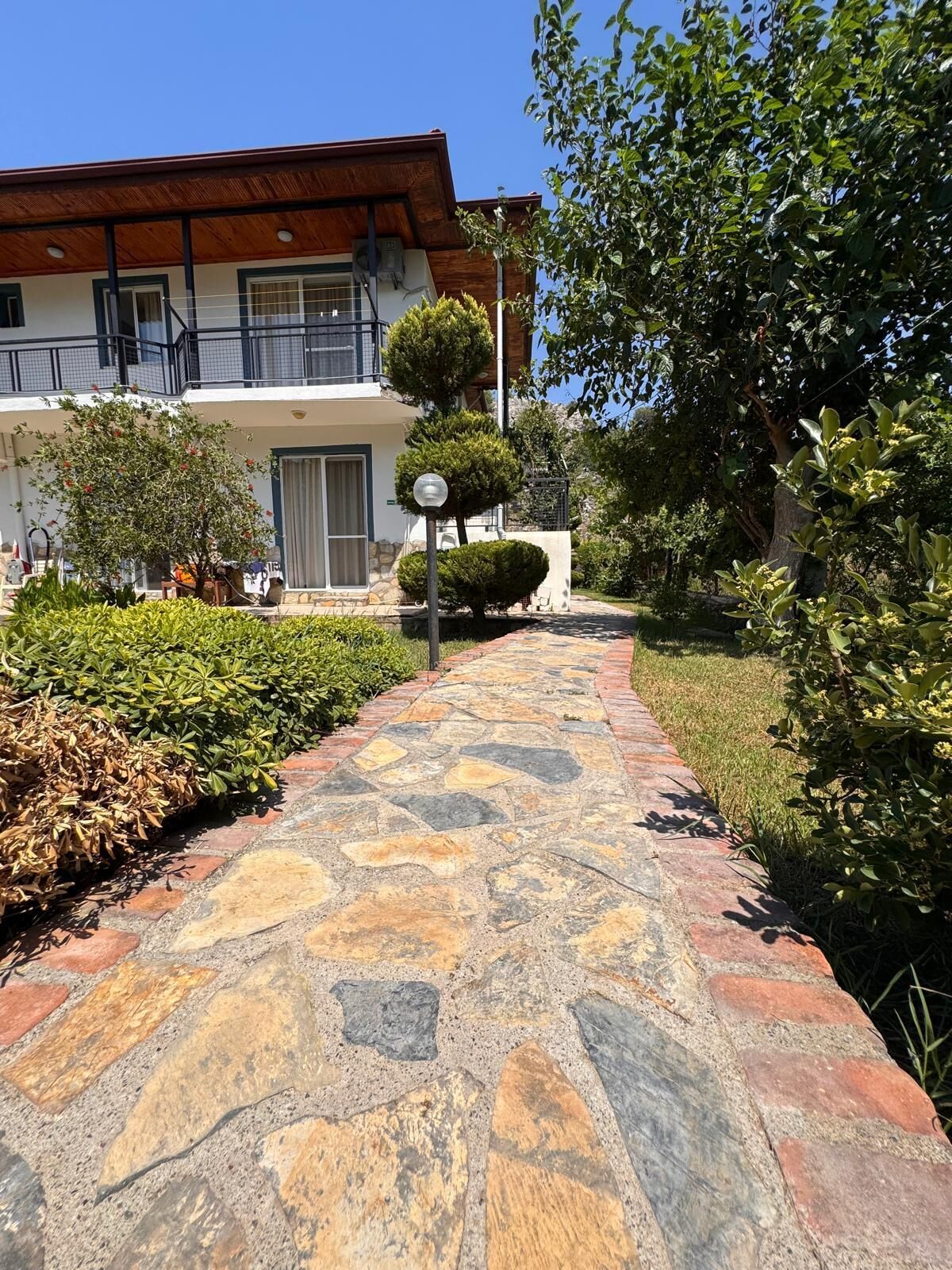 A stone pathway leading to a building with a balcony.