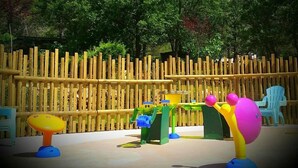 Un parque infantil con estructuras de juego coloridas y una valla de madera al fondo.