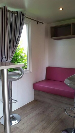 Quarto com sofá rosa, mesa de metal e janela com cortinas.