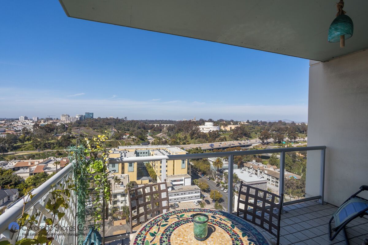 A balcony with a view of a cityscape, a tiled floor, and a hanging light fixture.