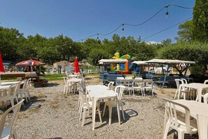 Guests can dine al fresco amidst lush surroundings and colorful play structures for kids.