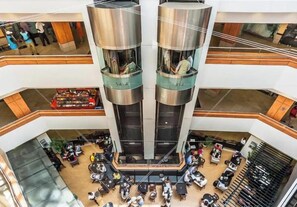 Useita tasoja käsittävä avoin aula, jonka keskellä on avoin tila, ja jonka ympärillä on oleskelualueita sekä ruokapaikkoja.