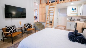 Makuuhuoneessa on suuri sänky, televisio, työpöytä tuoleineen, portaikko ja keittiöalue.