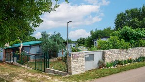 Une propriété dotée d’un mur en pierre, d’un portail en métal et d’un petit bâtiment surmonté d’un toit végétalisé.