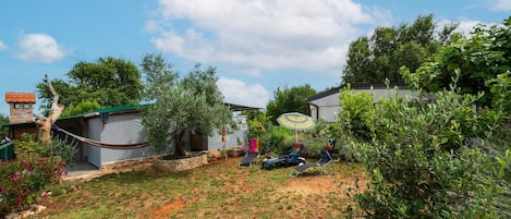 A backyard with a hammock, a small shed, and a patio area with a table and chairs.