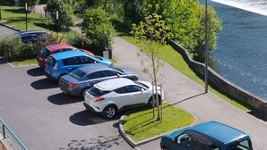 A parking area with several cars, a river, and a tower in the background. - Le Petit Valentré Avec sa Superbe vue sur le Célèbre Pont et la Rivière Lot (Cahors)