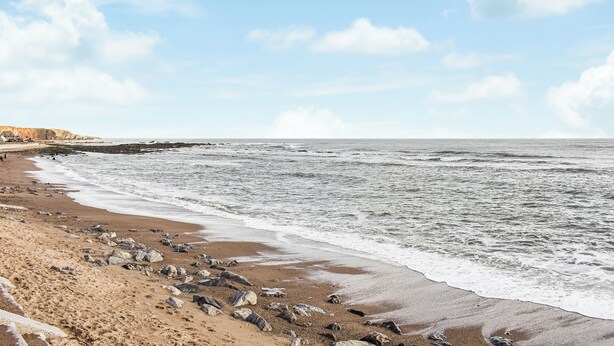 Ein Strand mit felsiger Küstenlinie und Wellen.