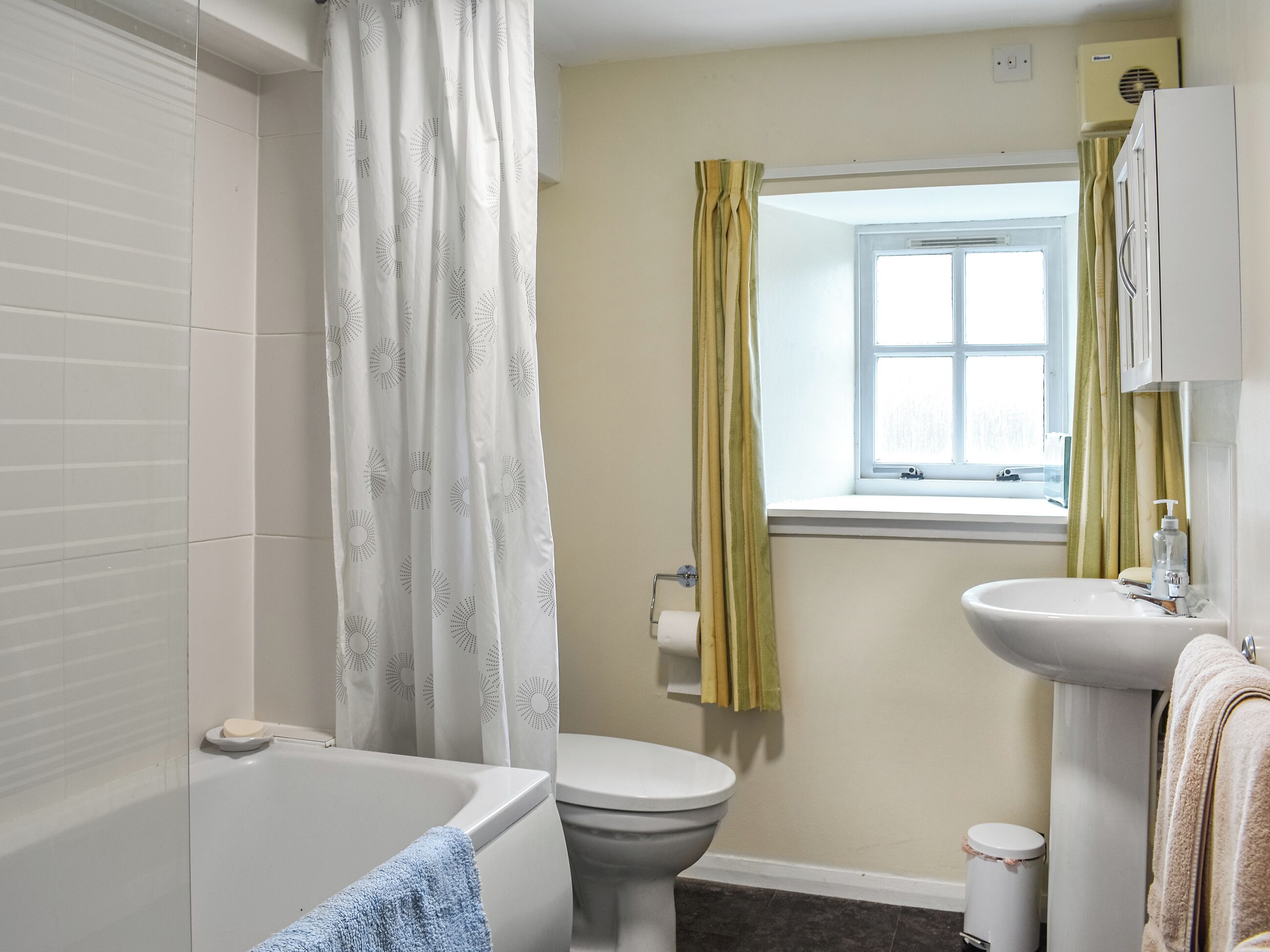 A bathroom with a bathtub, toilet, sink, and window.