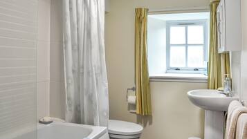 A bathroom with a bathtub, toilet, sink, and window.