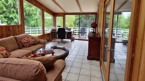 Una habitació espaiosa amb sostre de fusta, grans finestres, un sofà, una taula de cafè i vistes a l'exterior.