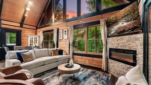 Una sala de estar acogedora con chimenea, ventanas amplias y una zona de estar confortable.