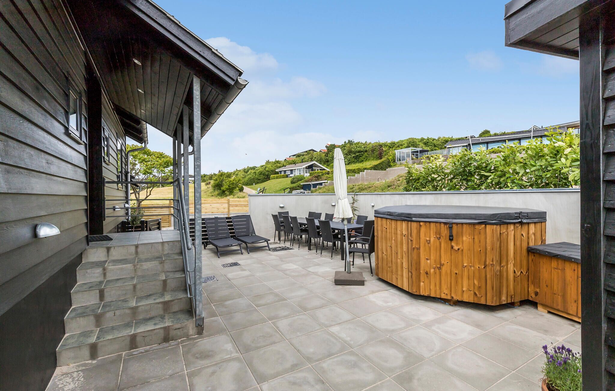 A patio with outdoor seating, a hot tub, and a view of a residential area.