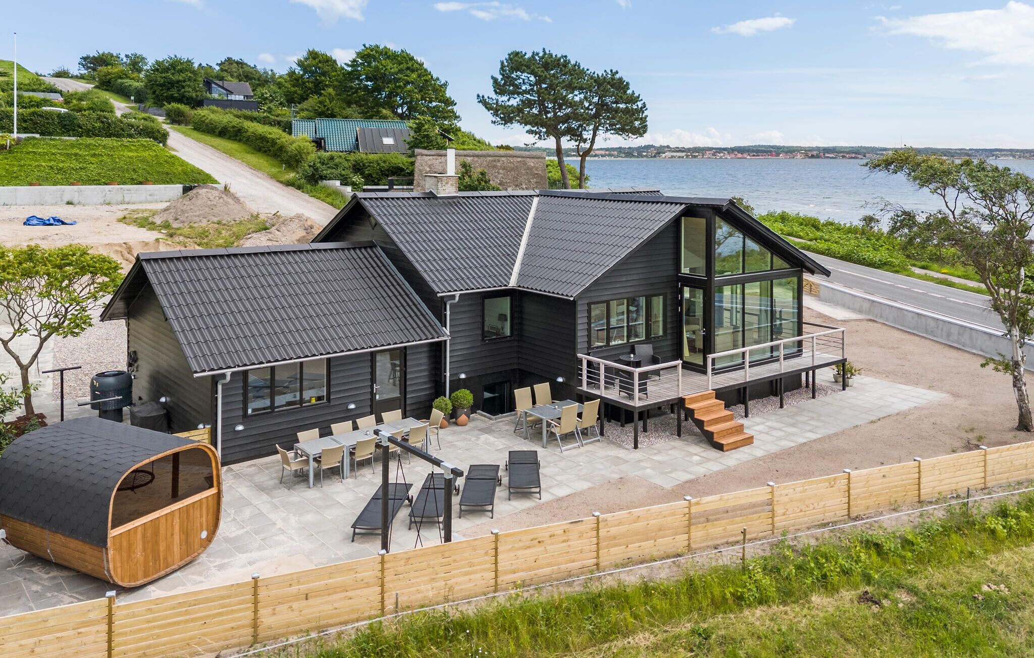 Een modern huis met een ruim terras, buitenmeubels en uitzicht op het water.