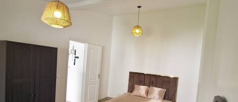 A bedroom with a bed, a wardrobe, a desk, and two pendant lights.
