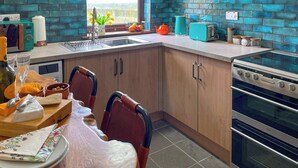 Une cuisine avec des meubles de rangement en bois, une fenêtre, une cuisinière et un grille-pain.