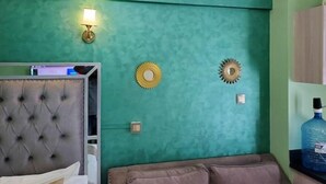 Una habitación con paredes verde azulado, un cabecero capitonado, un sofá y apliques decorativos en la pared.
