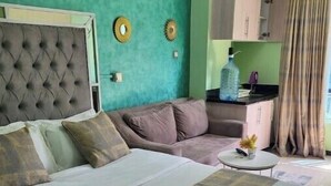Un dormitorio con una cama grande, un sofá, una pequeña mesa y una zona de kitchenette.