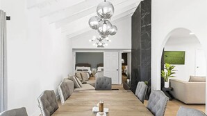 A spacious dining area with a long wooden table, grey upholstered chairs, and a modern chandelier. - Design Award Winner Scottsdale/Tempe Home POOL HTD

 (Tempe)