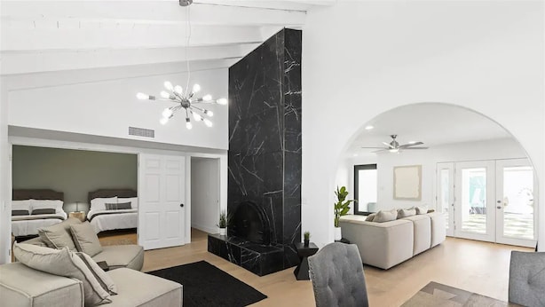 A spacious living area with a high ceiling, a black marble fireplace, and a modern chandelier. There are two sofas and a dining table. - Design Award Winner Scottsdale/Tempe Home POOL HTD

 (Tempe)