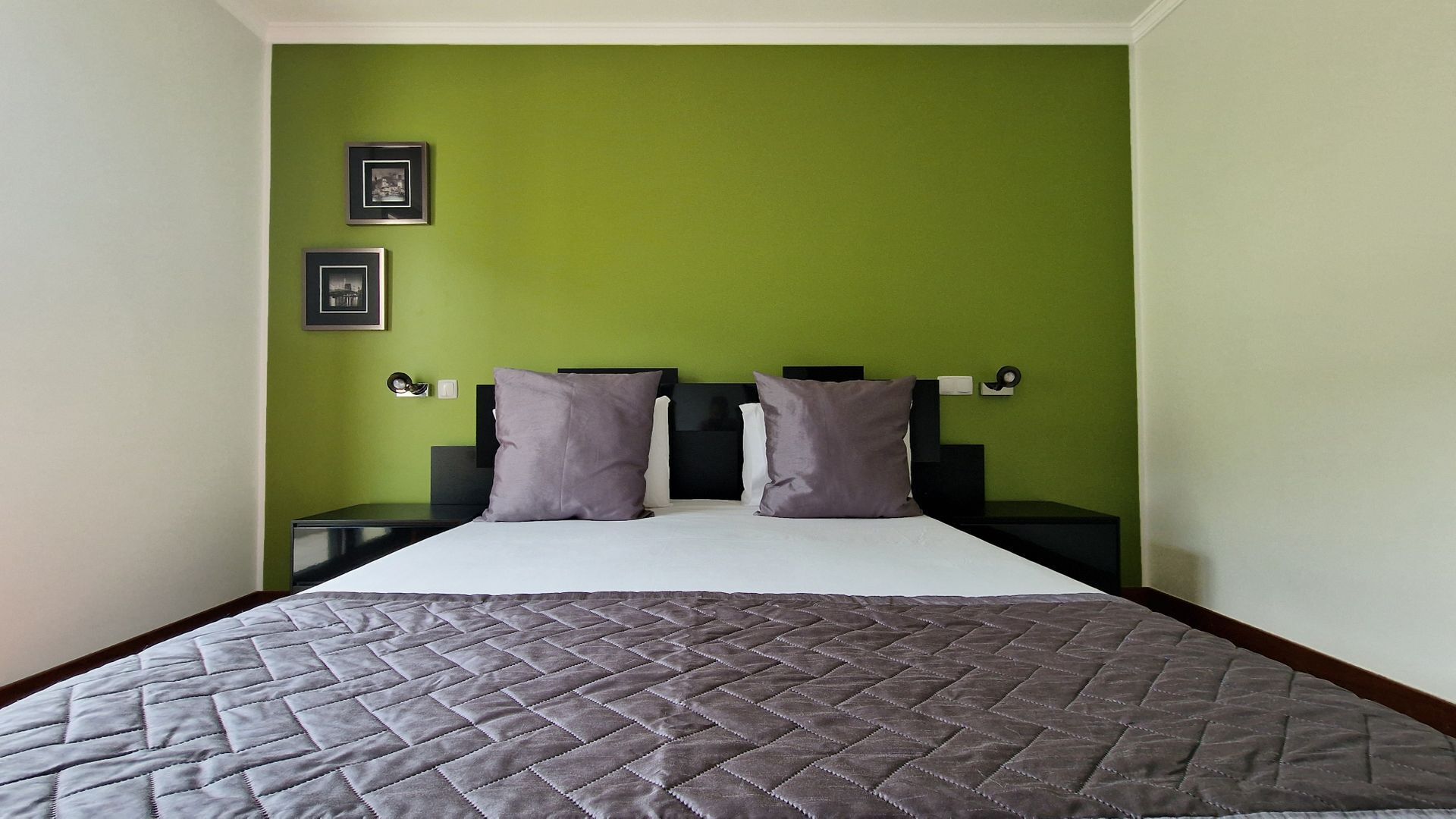 A bedroom with a bed, two nightstands, and green walls.