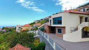 A modern two-story house with a curved staircase, a balcony, and a view of the sea. - Capelas House by LovelyStay (Campanario)