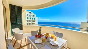 Un balcon avec une table préparée pour le petit-déjeuner, un ananas et une vue sur l’océan.