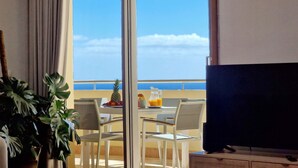 Un balcon avec une table préparée pour le petit-déjeuner, un ananas et une carafe de jus d’orange.