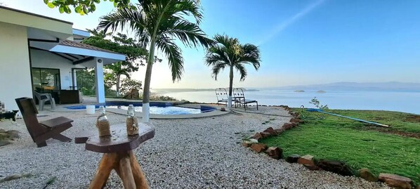 Un área de piscina con hidromasaje, sillones de descanso y vistas al mar.
