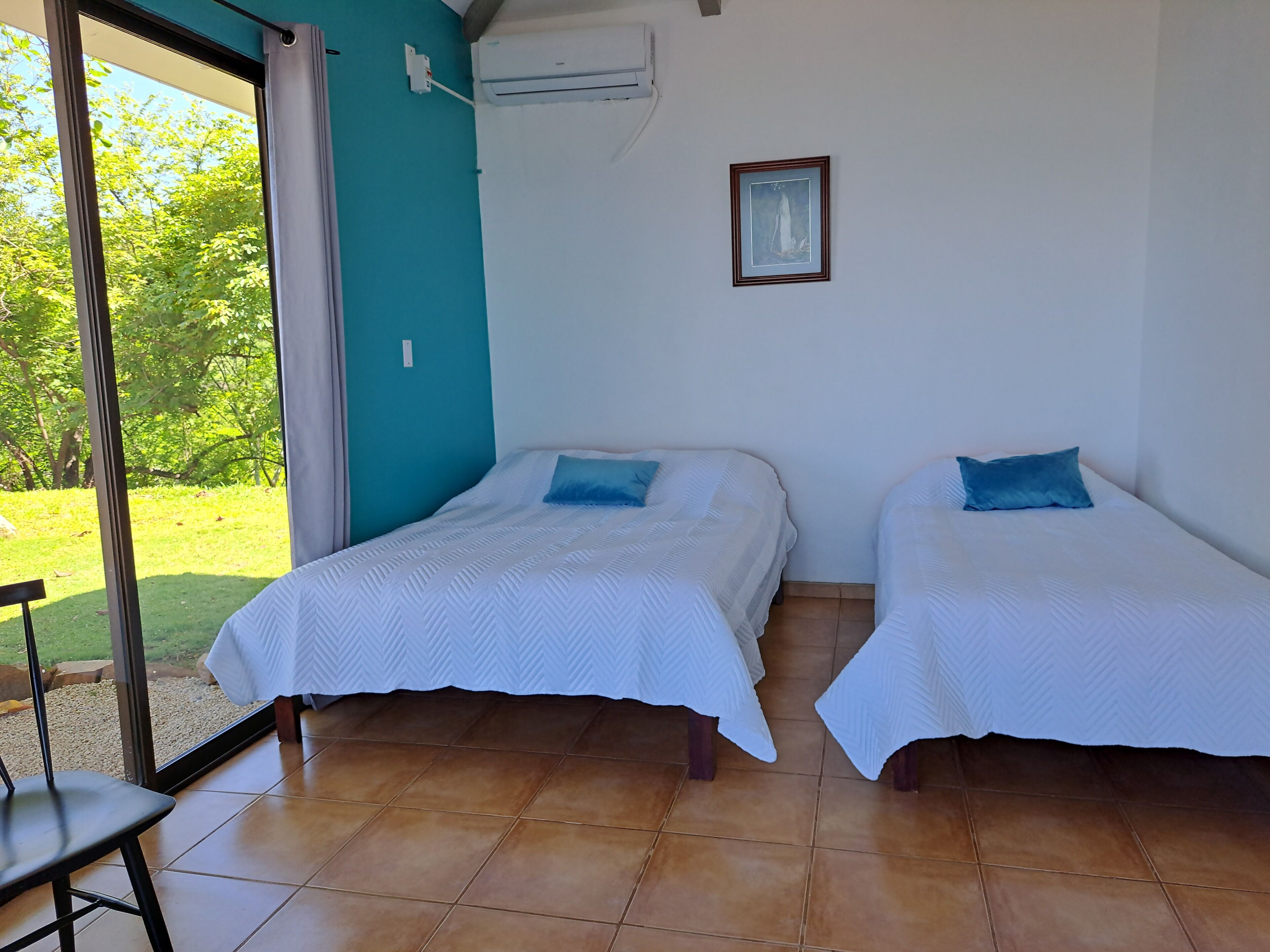 A room with two beds, a window, and an air conditioning unit.