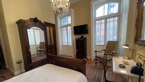 A spacious bedroom with a large bed, a chandelier, a television, and a desk with a telephone. - Casa Chopo (Mexico City)
