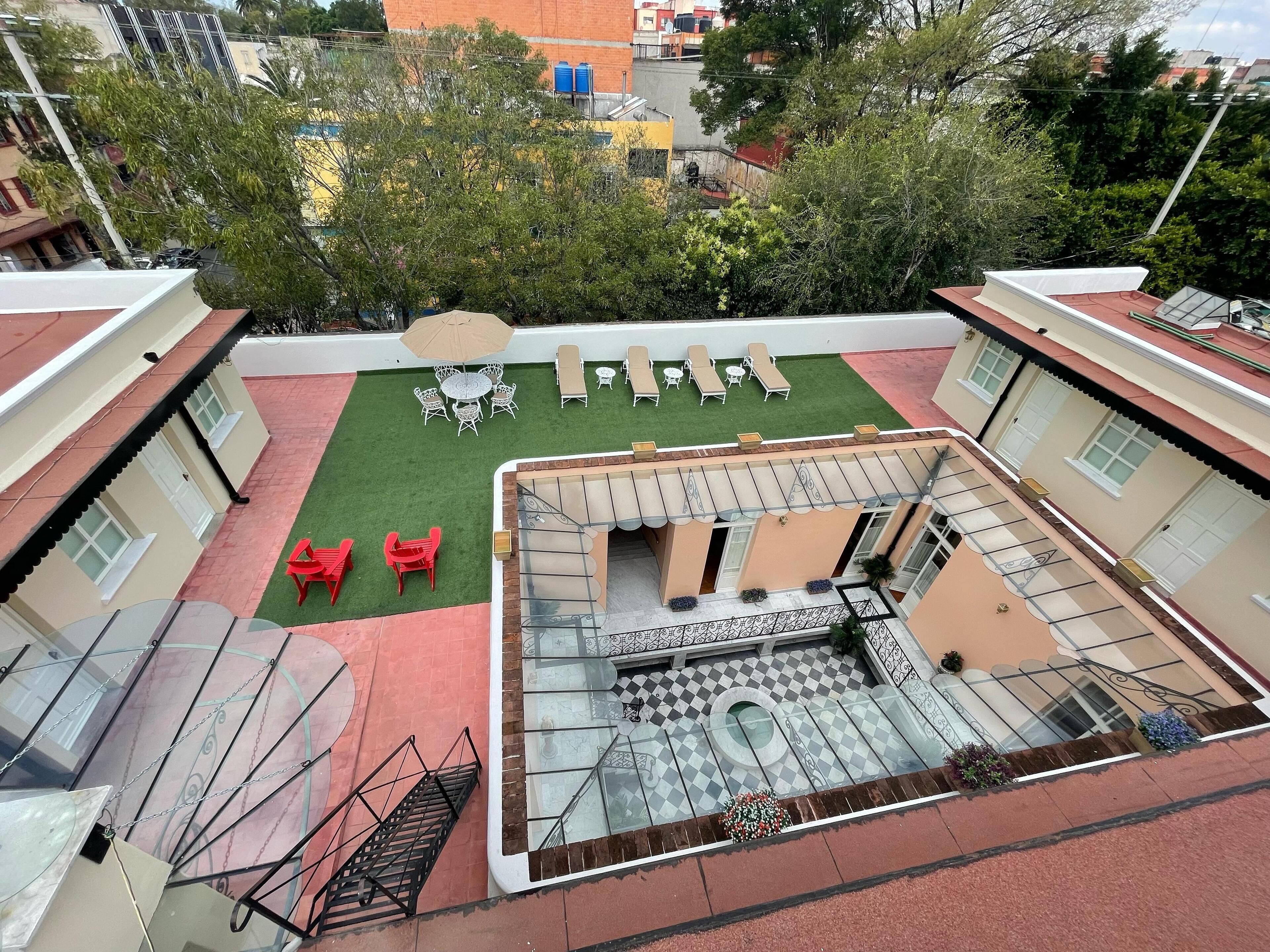 Eine Dachterrasse mit Sitzgelegenheiten im Freien, einem kleinen Gartenbereich und einem Pool.