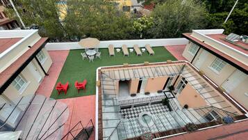 Eine Dachterrasse mit Sitzgelegenheiten im Freien, einem kleinen Gartenbereich und einem Pool.