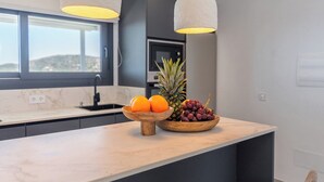 A kitchen island with a fruit bowl containing oranges and grapes, a pineapple, and a wooden bowl. - Villa El Retiro de Torrox by Ruralidays (Málaga)